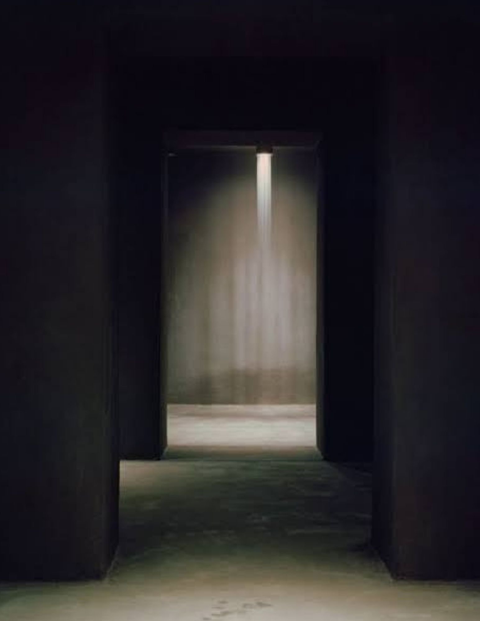 A bronze threshold at Riela Madrid opening into a lit bathing chamber with a falling wall of light