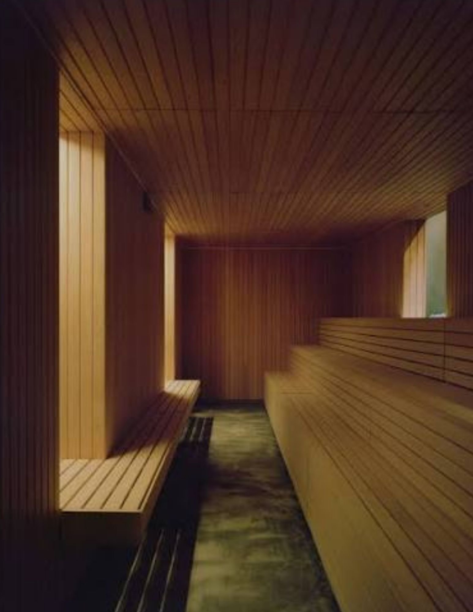 A wood-clad quiet room at Riela Madrid glowing with warm amber light and a single light slot
