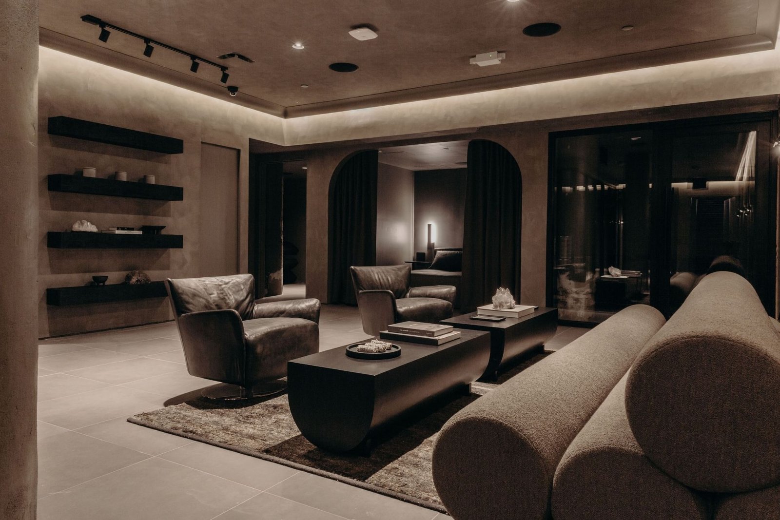 Remedy Place reception lounge with leather swivel chairs, a bouclé daybed and a curtained arched doorway