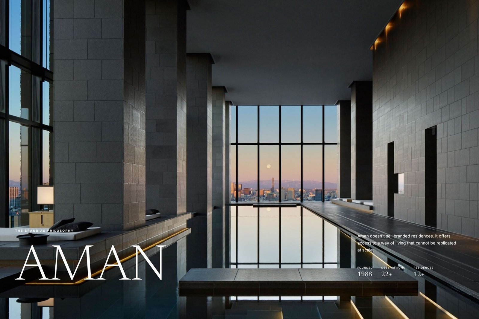 Aman brand slide: a serene high-rise infinity pool in Tokyo at dusk, framed by grey stone columns, the moonlit skyline reflected in the water, with the AMAN wordmark and the label 'The Brand as Philosophy'.