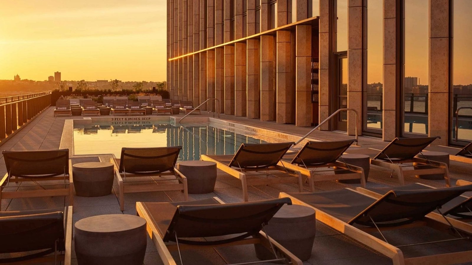 Empty rooftop lap pool and sun deck above the city at sunset