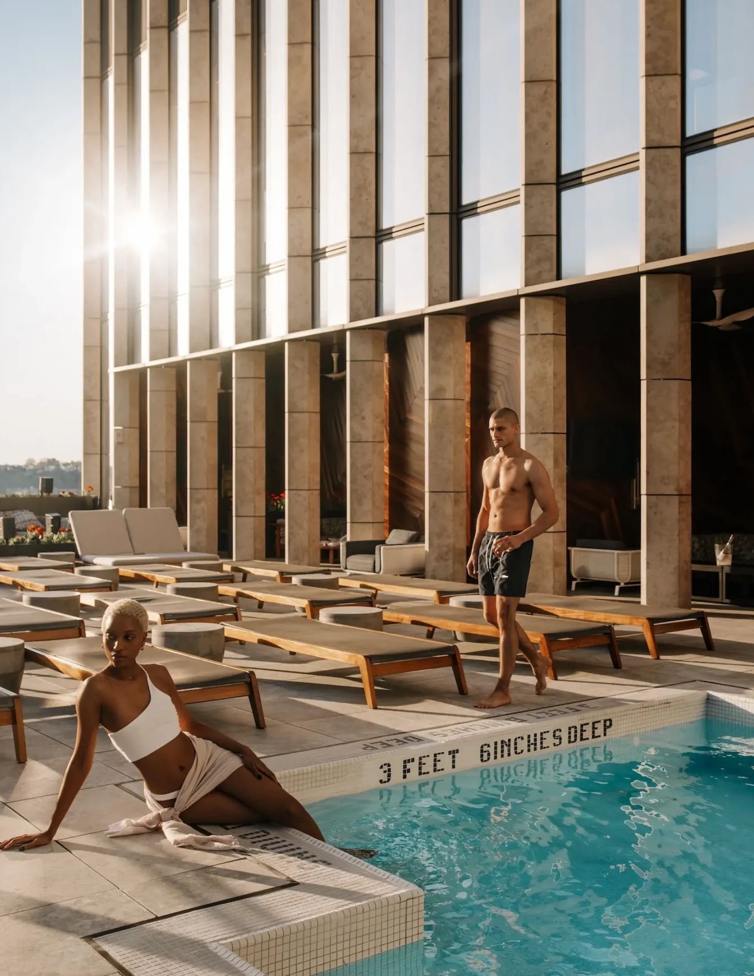 Two guests on the Equinox rooftop pool deck at golden hour